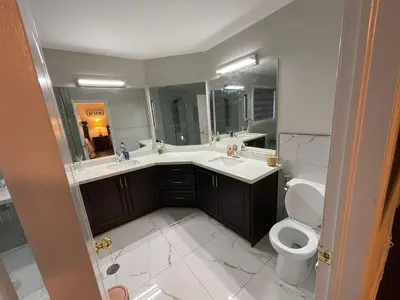 a bathroom with a toilet and a sink and mirror at Grandeur Homes in Whitby