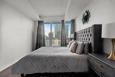 a bedroom with a bed and a large window at Modern 1Bd & Den Condo with Balcony Lillian St in Toronto