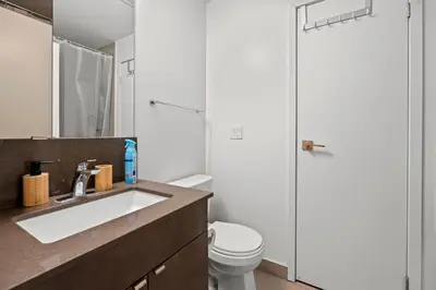 a bathroom with a sink and a toilet and a mirror at Modern 1Bd & Den Condo with Balcony Lillian St in Toronto