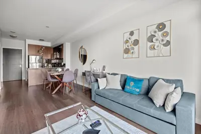 a living room with a blue couch and a table at Modern 1Bd & Den Condo with Balcony Lillian St in Toronto