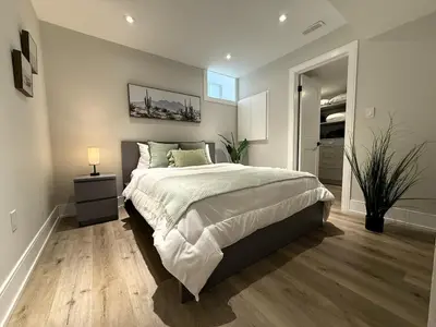 a bedroom with a large bed and a night stand with a lamp at Stylish 1BR in Queen West in Toronto