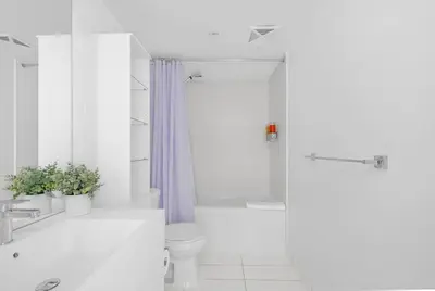 a white bathroom with a toilet and a shower at Spacious Retreat Luxe 3BR Condo with City Views in Toronto
