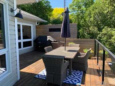 a patio with an umbrella and chairs on a deck at Luxurious Lakefront Cottage, Sleeps 12 in Bewdley
