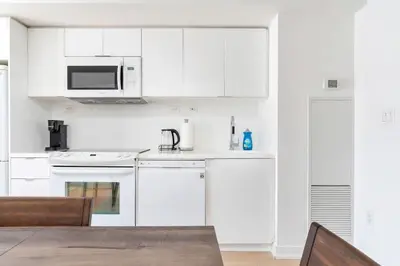 a white kitchen with white appliances and a table at Charming Condo w Private Patio in Quiet Capreol in Toronto