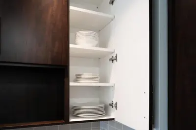 a cupboard filled with white plates and a tv at Modern 2BR in TO Near Yorkville & the Village in Toronto