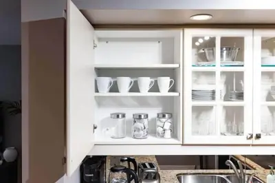 a kitchen with white cabinets with cups and dishes at Modern Oasis Stylish 2BR Condo Near Attractions in Toronto
