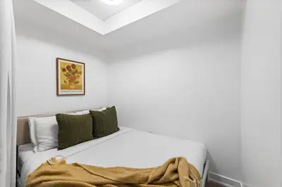 a bedroom with a white bed with a blanket on it at Modern & Stylish Comfort in the Heart of Toronto in Toronto