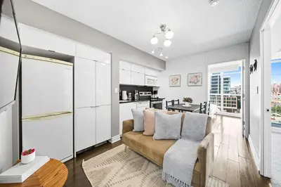 a living room with a couch and a kitchen at Spacious Toronto Condo w Patio - City Comfort in Toronto