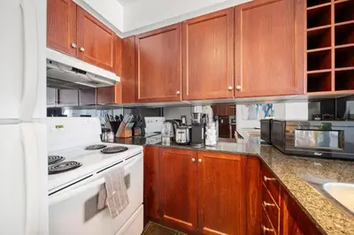 a kitchen with wooden cabinets and a white stove top oven at Chic 1BR Downtown Getaway w King Bed in Toronto