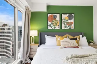 a bedroom with a green wall with a bed and a window at Yonge and Dun condo in Toronto