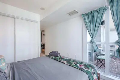 a bedroom with a bed and a large window at Modern 2 Bedroom plus Den Condo with Balcony Downtown Toronto in Toronto