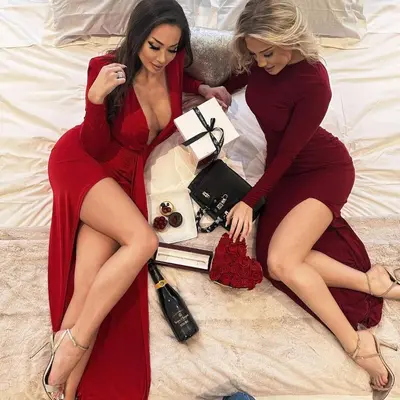 two women in red dresses sitting on a bed at Camden Haus Loft in Toronto