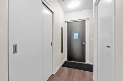 a hallway with a black door and white walls at luminous 2-Bedroom Apartment with Balcony in Toronto