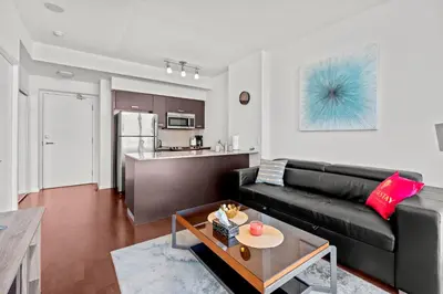 a living room with a black couch and a kitchen at Magnificent 1 Bd High floor view Downtown Toronto in Toronto