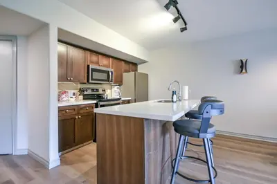 a kitchen with a white counter and a blue stool at 2BR King Suite Pool Sauna Heated Pool in Shanty Bay