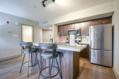 a kitchen with a counter with stools and a refrigerator at 2BR King Suite Pool Sauna Heated Pool in Shanty Bay