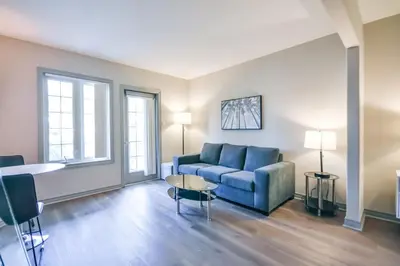 a living room with a blue couch and two windows at The King Studio Sauna Haven in Shanty Bay