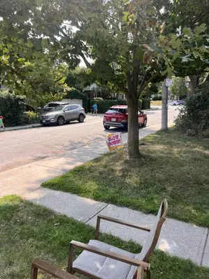 a wooden bench sitting on the grass next to a street at Entire 2BR Apt in Midtown Toronto, walk to Subway & Shops in Toronto