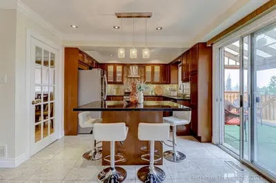 a kitchen with a large island with bar stools at Prestige Manor, 6BR with Sunroom and 3400 Sqft by Instant Suites in Mississauga