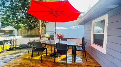 a table with chairs and a red umbrella on a patio at Comfortable waterfront vacation Keswick in Georgina
