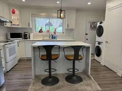 a kitchen with white cabinets and a island with two bar stools at Comfortable waterfront vacation Keswick in Georgina