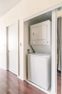 a washer and dryer in a room with a wall at Classic 1BR & Den Apartment in Downtown Gym Pool in Toronto