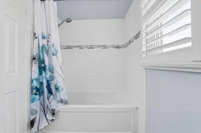 a white bathroom with a shower with a shower curtain at Backyard Oasis in Bradford