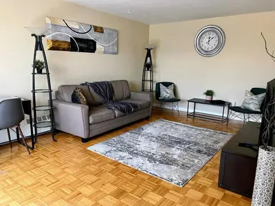 a living room with a couch and a clock on the wall at Bright 2 BR pet friendly, KING bed, WiFi,2 parking in Kitchener
