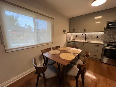 a kitchen with a wooden table and chairs and a window at Adrian's Suites 2 Bedroom FamilySuite in Wasaga Beach