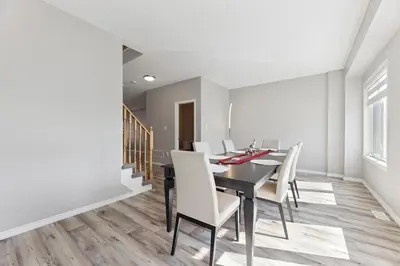 a dining room with a black table and white chairs at The Devineridge Executive House in Ajax