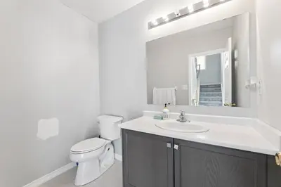 a white bathroom with a toilet and a sink at The Devineridge Executive House in Ajax