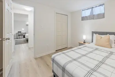 a white bedroom with a bed and a table at Stewarts Place Newly Renovated Basement City Apartment in Hamilton