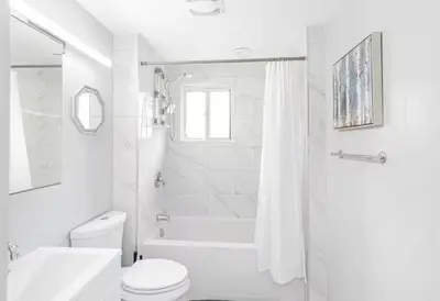 a white bathroom with a toilet and a shower at Quaint and Stylish UPPER level 3-bed bungalow in Hamilton, ON in Hamilton