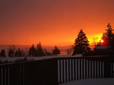 a sunset in the snow with a fence and trees at Eganridge Resort, Golf Club & Spa in Bobcaygeon