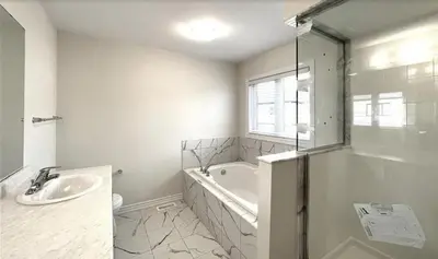 a white bathroom with a tub and a sink at New 3 Bedroom 2 Bathroom Home in West Niagara in Thorold