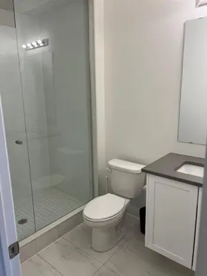 a bathroom with a toilet and a glass shower at Bowmanville Room in Bowmanville