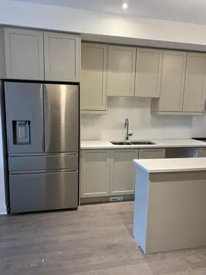 a kitchen with white cabinets and a stainless steel refrigerator at Bowmanville Room in Bowmanville