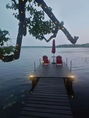 two chairs and an umbrella on a dock on a lake at Pet friendly- Crystal Water fishing Family Retreat in Havelock