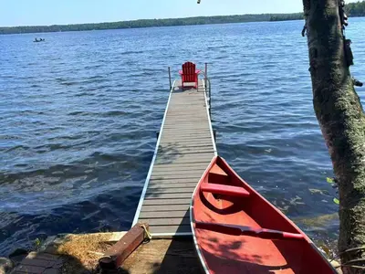 a wooden pier with a red boat on the water at Pet friendly- Crystal Water fishing Family Retreat in Havelock