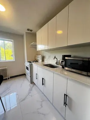 a kitchen with white cabinets and a sink and a microwave at Upper Beaches Apartment in Toronto