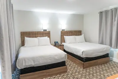 a hotel room with two beds with white sheets at Sunrise Motel in Owen Sound