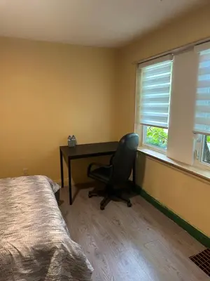 a bedroom with a desk and a chair in front of a window at Tom home in Toronto