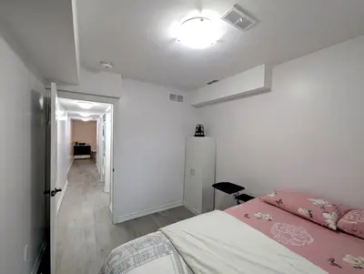 a white bedroom with a bed and a hallway at Bright & New 2 Beds Near Subway in Toronto