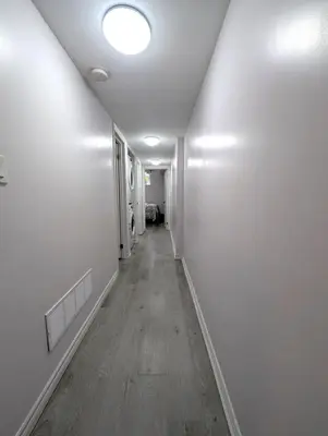 a hallway with white walls and a wooden floor at Bright & New 2 Beds Near Subway in Toronto