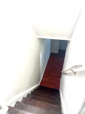 a stairway with a white wall and wooden floors at Quincy Home in Mississauga