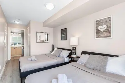 a bedroom with two beds and a living room at SkyView 2BR Plus Den Stunning Views Steps to SQ1 Mall in Mississauga