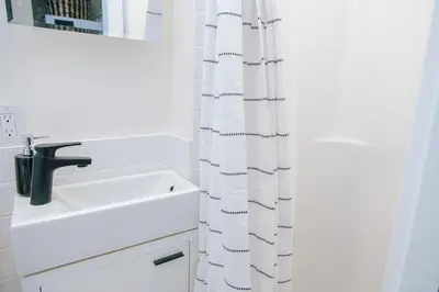 a white bathroom with a sink and a shower curtain at Dundas and Brock Suitel in Toronto