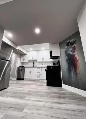 a kitchen with white cabinets and a painting on the wall at Modern Suite in Etobicoke - Near Airport & Downtown! in Toronto
