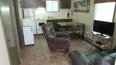 a living room with a couch and a table and a kitchen at The Maples Cottages in Port Elgin in Port Elgin