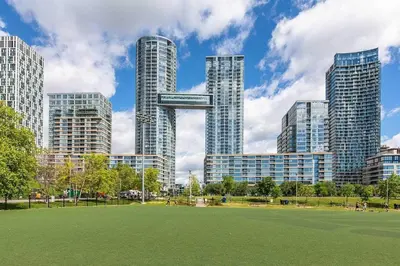 a park in front of a city with tall buildings at The Nest in Toronto